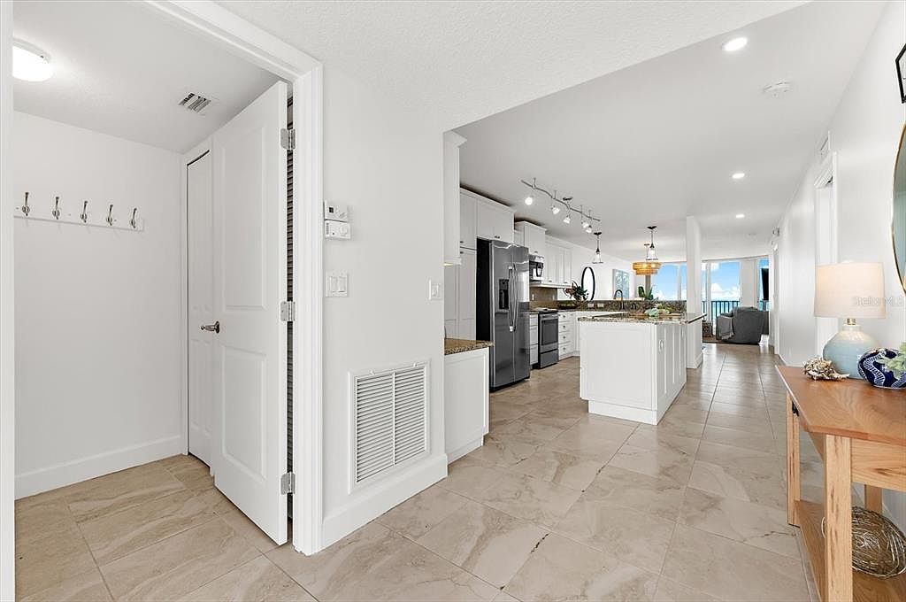 Interior view of Unit 33 with the remodeled white shaker kitchen and island center-frame, stainless appliances, and the Gulf visible through the far living-room windows